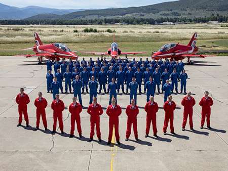 Image shows the Red Arrows Team in front of three Red Arrow Hawks.