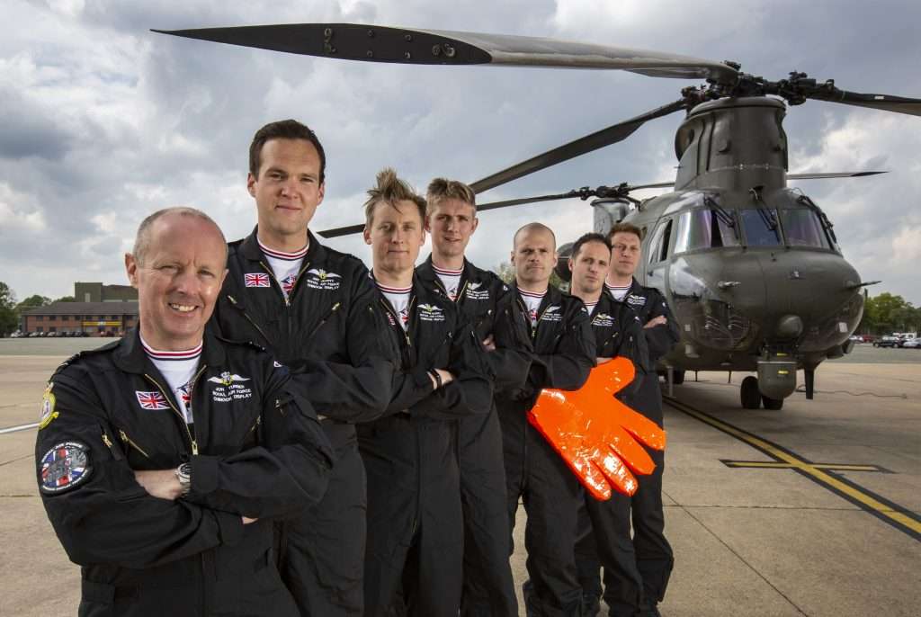 The RAF Chinook Display Team stood infront of a Chinook with the loadmaster holding a big orange foam hand.
